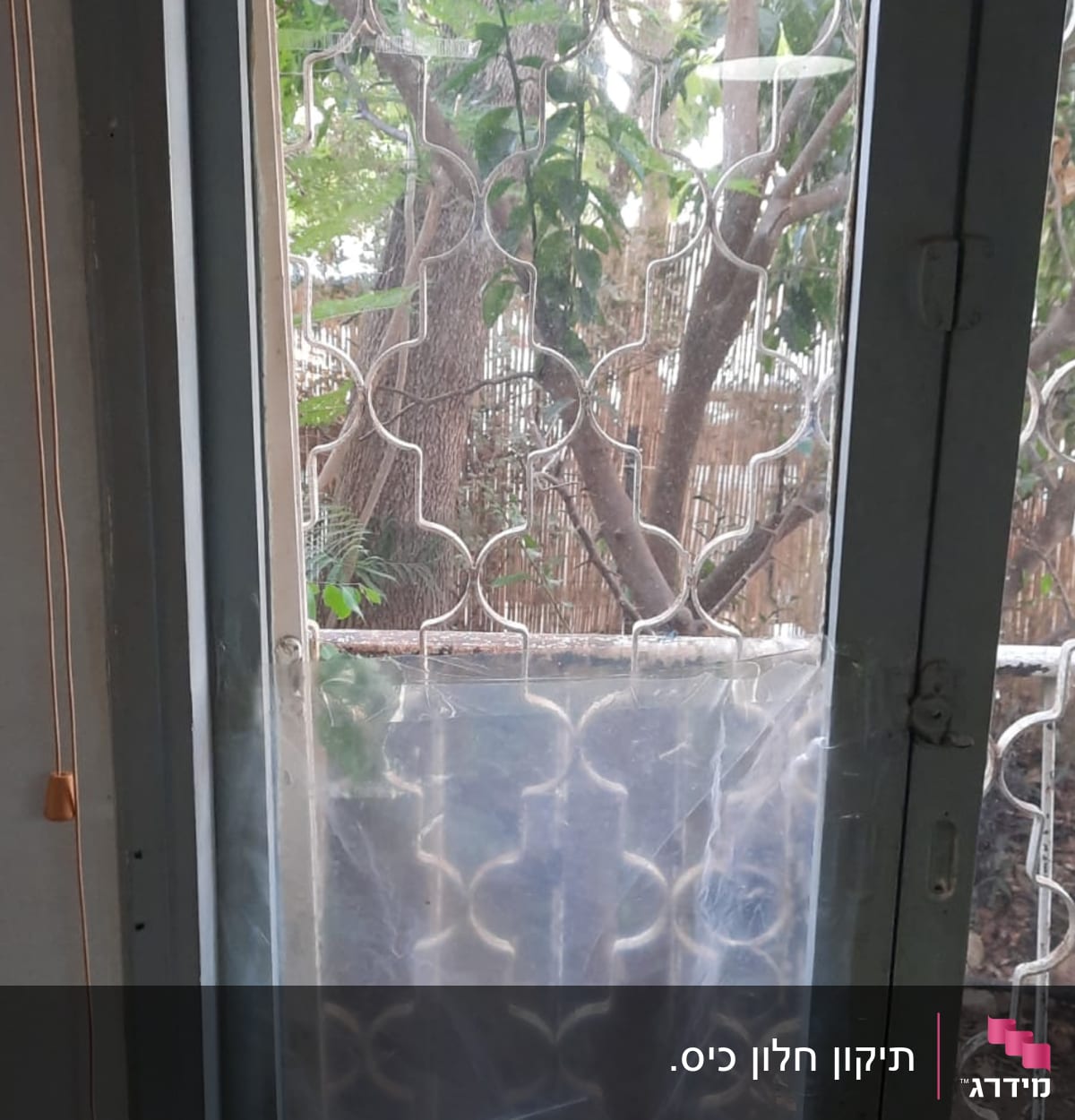 חלון זכוכית עם דוגמה גיאומטרית וברקע עצים